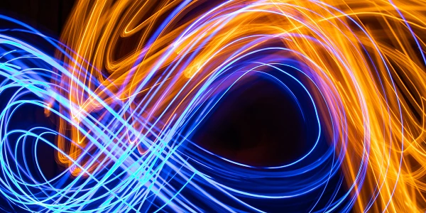 Dynamische Lichtspuren in Orange und Blau auf schwarzem Hintergrund