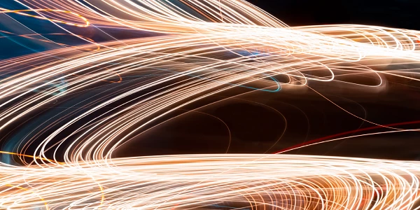 Bright curved light trails on dark background