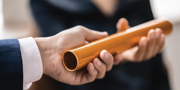 Staffelstab wird zwischen zwei Händen übergeben, symbolisch für Übergabe